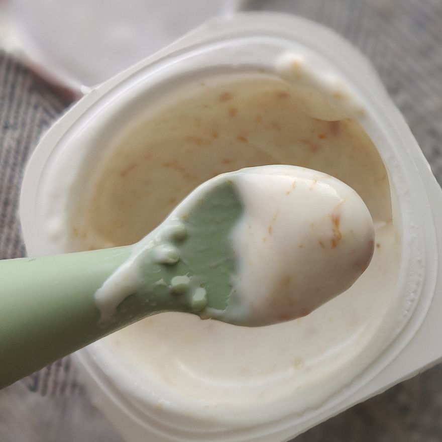 Colher de silicone com papa cremosa apoiada na taca, pronta para a refeicao do bebe